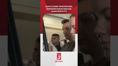 Uçakta maske yapan iki kadın, kendilerine şaşkın şaşkın bakan gençlere