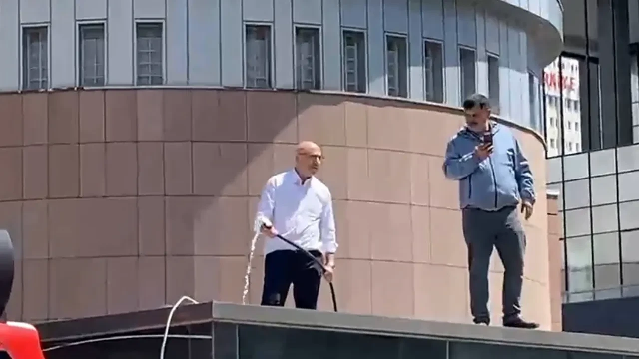 Mahmut Tanal, su hortumuyla parti binasının önündeki güvenlik kulübesinin üstüne